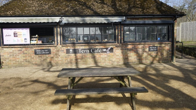 Front view of Tern cafe brick building, with two serving hatches at each end and a picnic bench in the foreground.